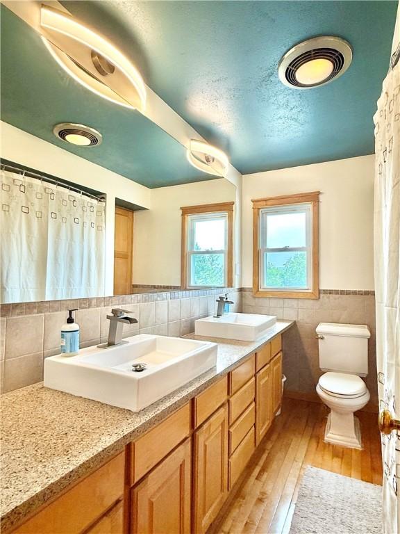 3 Suncrest Ter, Oneonta-City, NY 13820 - bathroom featuring tile walls, double vanity, hardwood / wood-style floors, and wainscoting