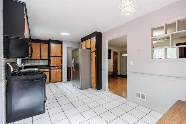 77 Chad Cir, Greece, NY 14616 - kitchen featuring stainless steel refrigerator with ice dispenser, light tile patterned flooring, black range, backsplash, and brown cabinetry