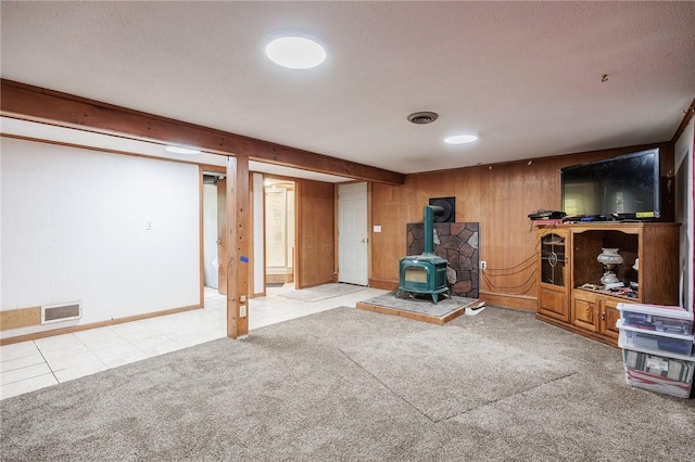 77 Chad Cir, Greece, NY 14616 - unfurnished living room featuring a wood stove, wood walls, carpet, and tile patterned flooring