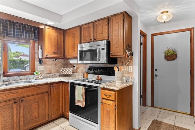 133 Parklands Dr, Greece, NY 14616 - kitchen featuring stainless steel microwave, white range with electric stovetop, light tile patterned floors, and brown cabinetry