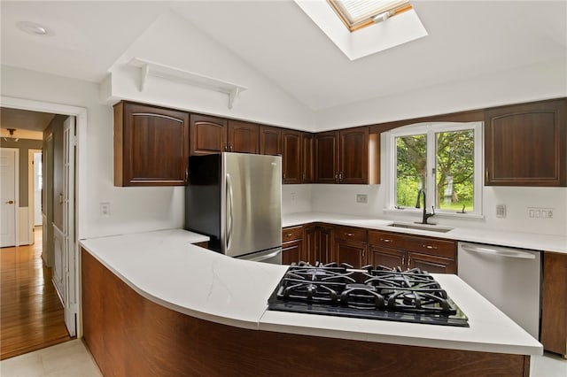 38 Moroa Dr, Irondequoit, NY 14622 - kitchen featuring stainless steel appliances, a skylight, light countertops, vaulted ceiling, and dark brown cabinetry