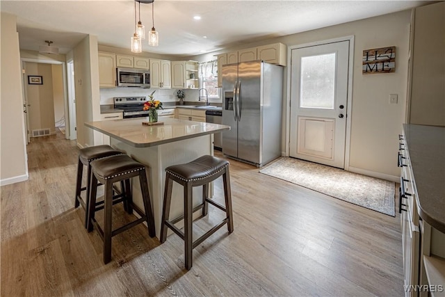 1558 Youngstown Wilson Rd, Porter, NY 14174 - kitchen with stainless steel appliances, light wood-style flooring, a breakfast bar area, hanging light fixtures, and a center island
