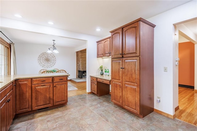 16 Clearview Dr, Henrietta, NY 14534 - kitchen featuring a brick fireplace, a chandelier, decorative light fixtures, brown cabinetry, and recessed lighting