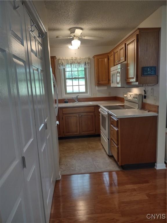 407 Fultz Dr, Oneida-Inside, NY 13421 - kitchen with white electric stove, light countertops, brown cabinetry, ceiling fan, and a textured ceiling