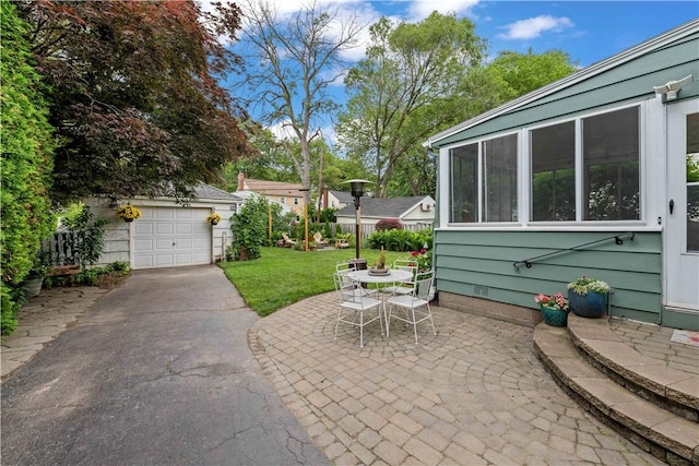 30 Northfield Rd, Irondequoit, NY 14617 - view of patio / terrace featuring asphalt driveway, a garage, an outbuilding, and outdoor dining space