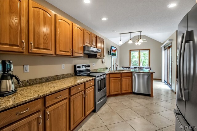 139 Autumn Creek Ct, Amherst, NY 14051 - kitchen featuring stainless steel appliances, under cabinet range hood, brown cabinetry, lofted ceiling, and a peninsula