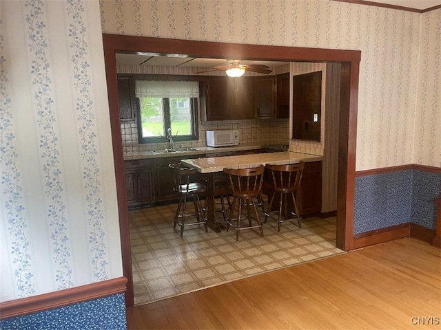 205 Morton St, Syracuse, NY 13204 - kitchen with white microwave, light wood-style floors, light countertops, a breakfast bar, and a peninsula