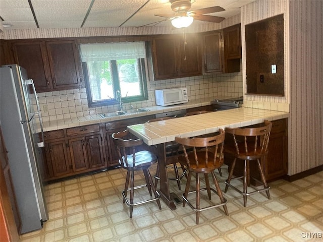 205 Morton St, Syracuse, NY 13204 - kitchen featuring freestanding refrigerator, light flooring, white microwave, tile counters, and ceiling fan