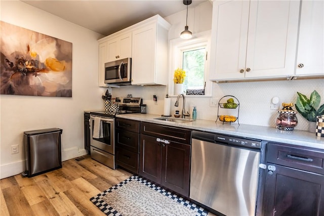 94 Birchwood Dr, Irondequoit, NY 14622 - kitchen with stainless steel appliances, white cabinets, backsplash, light wood-style flooring, and decorative light fixtures