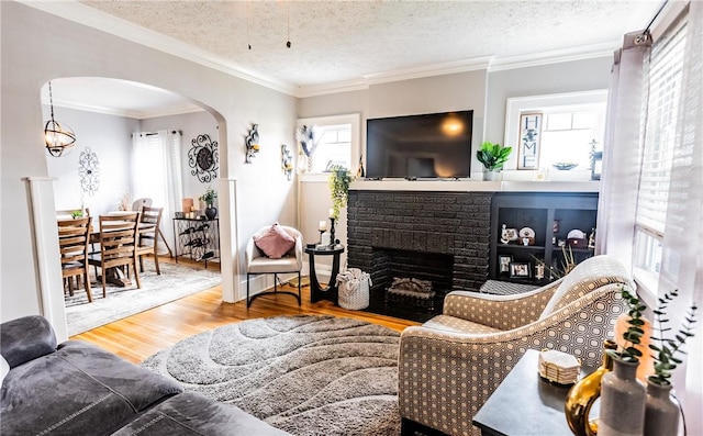 94 Birchwood Dr, Irondequoit, NY 14622 - living room featuring arched walkways, wood finished floors, a brick fireplace, a textured ceiling, and crown molding