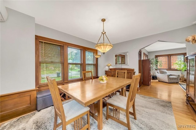 176 Mount Vernon Rd, Amherst, NY 14226 - dining room featuring arched walkways, light wood-type flooring, a wall unit AC, and wainscoting