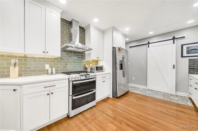 176 Mount Vernon Rd, Amherst, NY 14226 - kitchen featuring appliances with stainless steel finishes, wall chimney exhaust hood, a barn door, light countertops, and recessed lighting