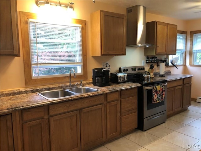1407 N James St, Rome-Inside, NY 13440 - kitchen with stainless steel electric stove, wall chimney exhaust hood, healthy amount of natural light, and brown cabinets
