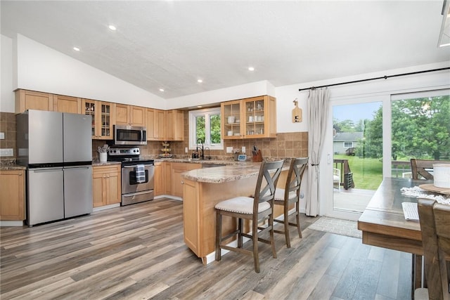 55 Creighton Ln, Greece, NY 14612 - kitchen with stainless steel appliances, light wood-style floors, vaulted ceiling, glass insert cabinets, and decorative backsplash