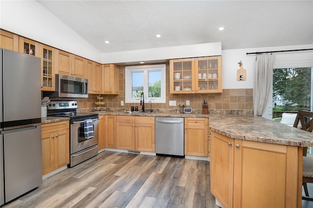 55 Creighton Ln, Greece, NY 14612 - kitchen with appliances with stainless steel finishes, a peninsula, light wood finished floors, decorative backsplash, and lofted ceiling