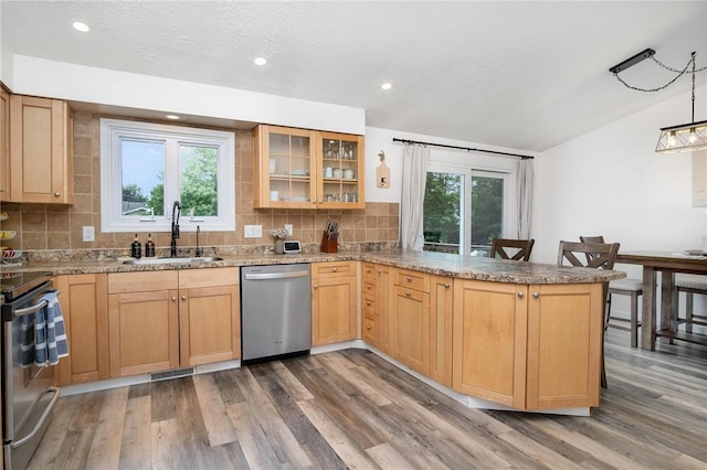 55 Creighton Ln, Greece, NY 14612 - kitchen featuring appliances with stainless steel finishes, vaulted ceiling, wood finished floors, decorative backsplash, and a peninsula