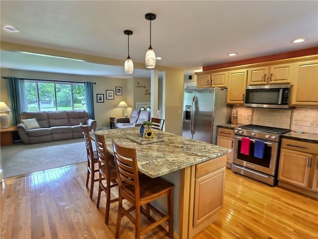 40 Ice Rose Ln, Henrietta, NY 14623 - kitchen with stainless steel appliances, open floor plan, a breakfast bar, light stone countertops, and light wood-style floors