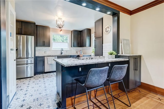 79 Rawlinson Rd, Irondequoit, NY 14617 - kitchen featuring appliances with stainless steel finishes, light stone counters, tasteful backsplash, a kitchen breakfast bar, and a peninsula