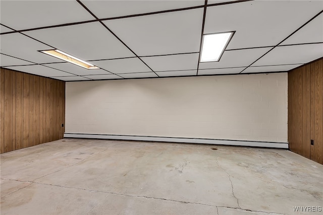 218 Hall Rd, Lancaster, NY 14059 - unfurnished room featuring baseboard heating, unfinished concrete floors, wood walls, concrete block wall, and a drop ceiling