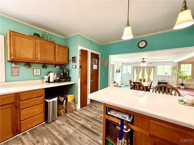 4935 N Jefferson St, Richland, NY 13142 - kitchen featuring brown cabinetry, light wood-style flooring, ceiling fan, pendant lighting, and ornamental molding