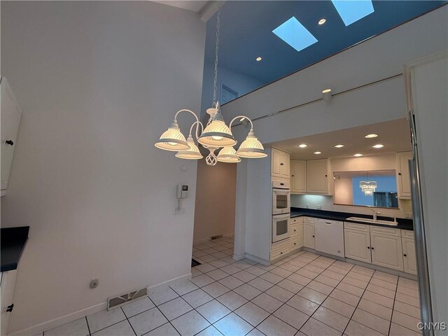 5326 Bunker Hill Way, Onondaga, NY 13207 - kitchen with a skylight, white appliances, dark countertops, a chandelier, and light tile patterned flooring