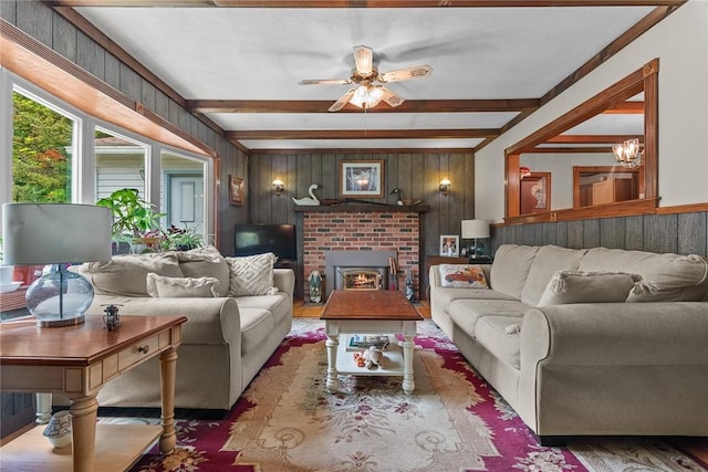 226 Academy St, Middletown, NY 12455 - living room featuring beam ceiling, wood finished floors, wood walls, a ceiling fan, and a brick fireplace