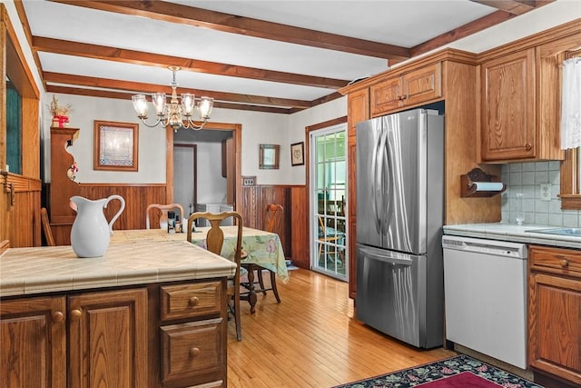 226 Academy St, Middletown, NY 12455 - kitchen with white dishwasher, freestanding refrigerator, beam ceiling, wainscoting, and brown cabinetry