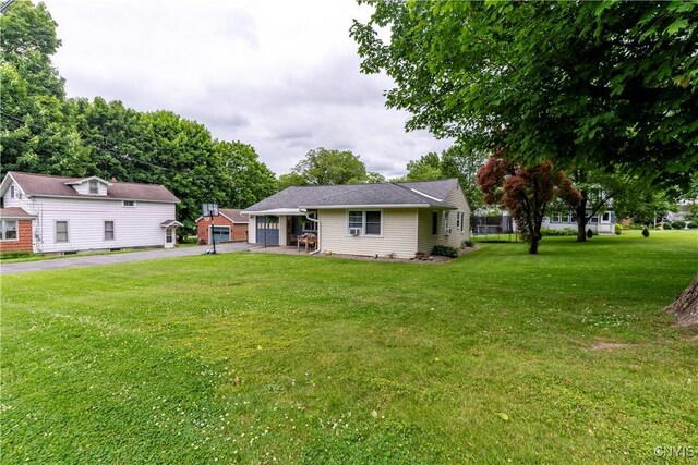 7 Bakeman St, Fulton, NY 13069 - rear view of house featuring driveway, a yard, and an attached garage