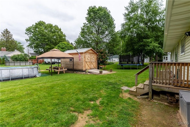 7 Bakeman St, Fulton, NY 13069 - view of green lawn featuring a trampoline, a storage unit, a gazebo, and a wooden deck