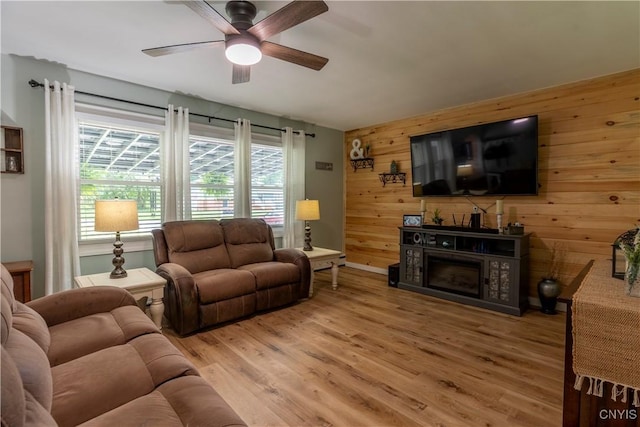 7 Bakeman St, Fulton, NY 13069 - living area with wooden walls, ceiling fan, light wood-style floors, an accent wall, and a fireplace