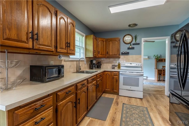 7 Bakeman St, Fulton, NY 13069 - kitchen featuring black appliances, brown cabinets, light wood-type flooring, light countertops, and decorative backsplash