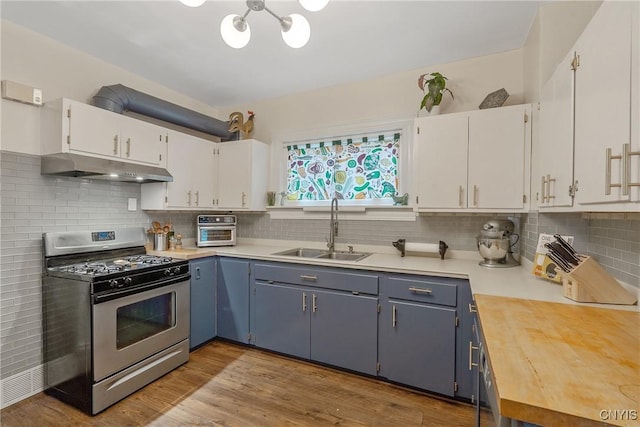 135 Strong Ave, Syracuse, NY 13210 - kitchen featuring stainless steel range with gas stovetop, under cabinet range hood, white cabinetry, tasteful backsplash, and wood finished floors