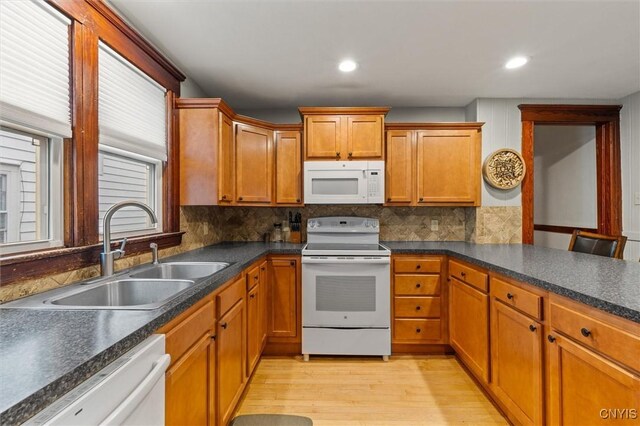 606 Tompkins St, Syracuse, NY 13204 - kitchen with white appliances, light wood-style floors, brown cabinetry, tasteful backsplash, and dark countertops
