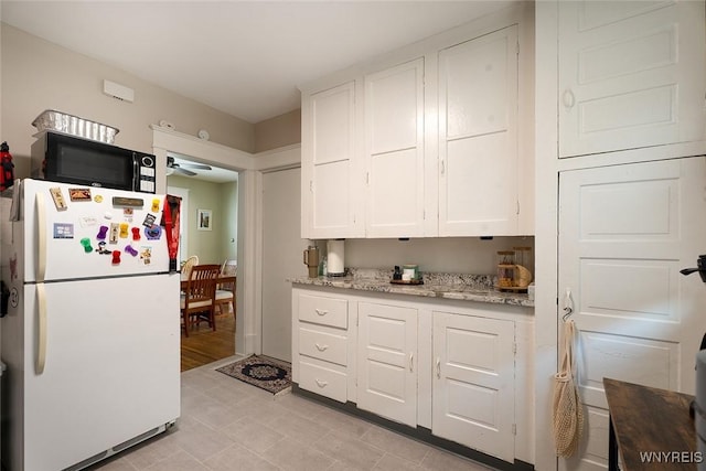 180 Lovering Ave, Buffalo, NY 14216 - kitchen featuring freestanding refrigerator, black microwave, white cabinets, a ceiling fan, and light tile patterned flooring