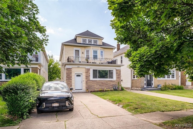 180 Lovering Ave, Buffalo, NY 14216 - american foursquare style home featuring a balcony, a front lawn, and stone siding