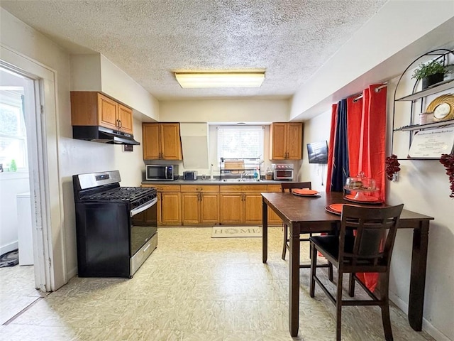 149 Post Ave, Rochester, NY 14619 - kitchen featuring appliances with stainless steel finishes, under cabinet range hood, a textured ceiling, brown cabinets, and light floors