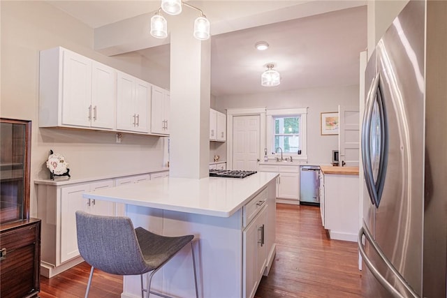 70 Field St, Rochester, NY 14620 - kitchen with appliances with stainless steel finishes, dark wood finished floors, white cabinetry, a kitchen island, and light countertops