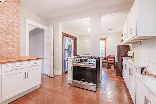 70 Field St, Rochester, NY 14620 - kitchen featuring appliances with stainless steel finishes, light wood finished floors, butcher block countertops, white cabinets, and pendant lighting