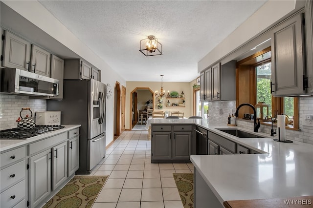 197 Shellridge Dr, Amherst, NY 14051 - kitchen featuring appliances with stainless steel finishes, gray cabinets, a chandelier, a peninsula, and backsplash