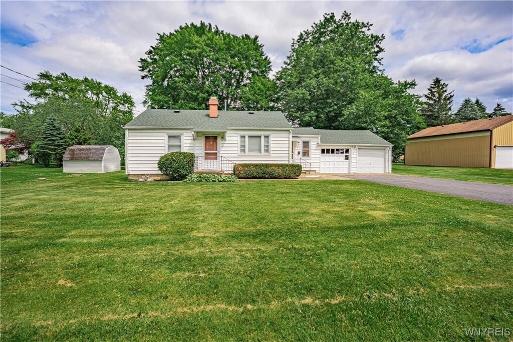 2659 Grace Ave, Newfane, NY 14108 - ranch-style home with driveway, a front yard, a storage shed, and an attached garage