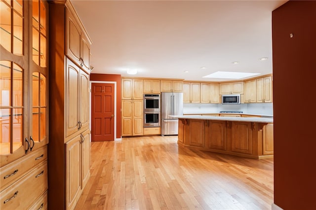 7175 Gale Rd, Lima, NY 14485 - kitchen with appliances with stainless steel finishes, a skylight, light wood-style flooring, a kitchen breakfast bar, and recessed lighting