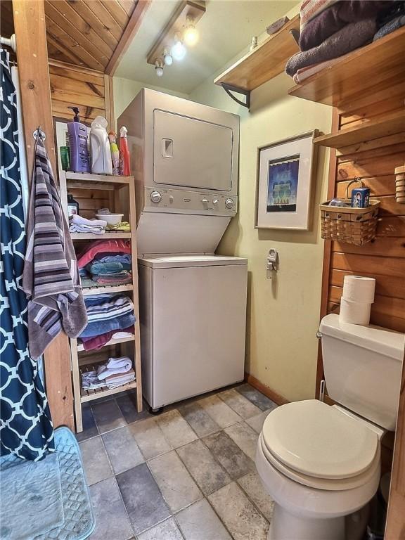 1995 Lake Rd, Ledyard, NY 13026 - bathroom featuring stacked washer / drying machine, stone finish floors, and a shower with shower curtain