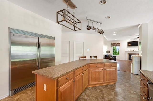 8278 Luchsinger Ln, Lysander, NY 13027 - kitchen with appliances with stainless steel finishes, ceiling fan, open floor plan, a kitchen island, and a fireplace