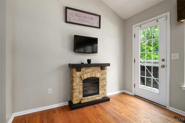 8278 Luchsinger Ln, Lysander, NY 13027 - unfurnished living room with hardwood / wood-style flooring, a stone fireplace, and vaulted ceiling