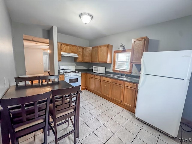 72 Groton Ave, Cortland, NY 13045 - kitchen with white appliances, under cabinet range hood, dark countertops, and light tile patterned flooring