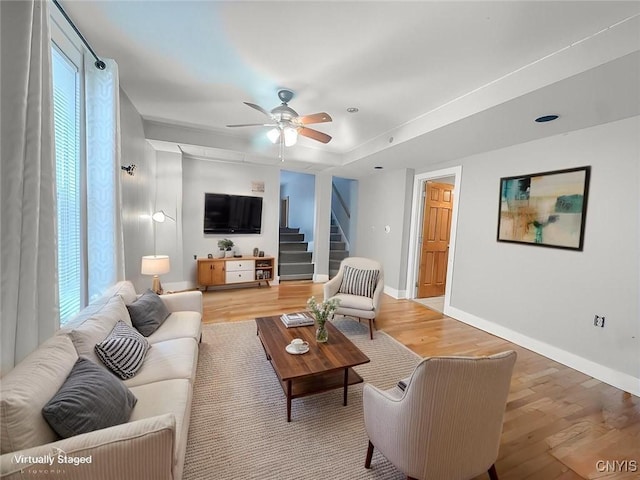 72 Groton Ave, Cortland, NY 13045 - living room featuring light wood finished floors, stairway, a ceiling fan, and healthy amount of natural light