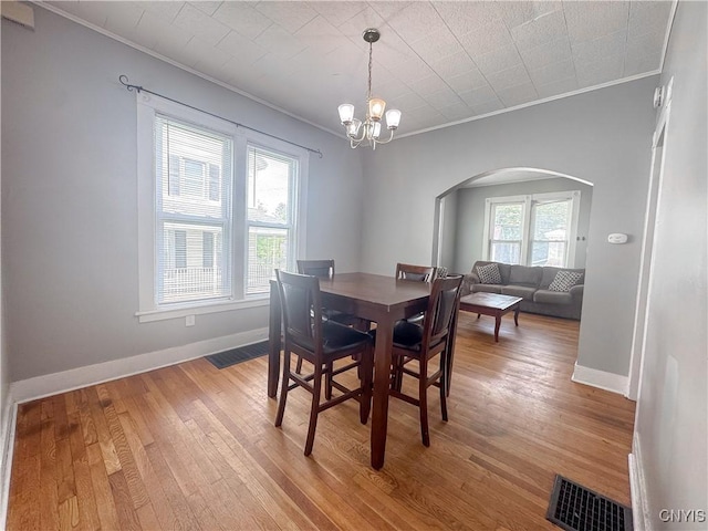 73 Groton Ave Unit 69-71, Cortland, NY 13045 - dining room with arched walkways, crown molding, light wood finished floors, and a chandelier
