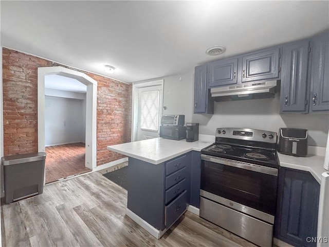 66 Groton Ave, Cortland, NY 13045 - kitchen with stainless steel electric range, under cabinet range hood, a peninsula, light countertops, and arched walkways