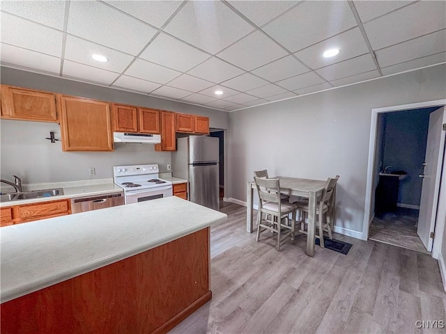 63 Groton Ave, Cortland, NY 13045 - kitchen with under cabinet range hood, appliances with stainless steel finishes, brown cabinetry, light countertops, and light wood-style floors