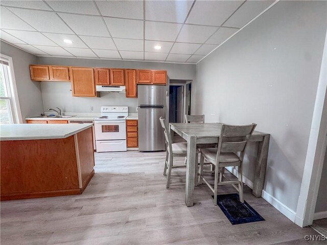 63 Groton Ave, Cortland, NY 13045 - kitchen with freestanding refrigerator, white range with electric cooktop, under cabinet range hood, light countertops, and light wood-style flooring